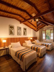 2 łóżka w pokoju z drewnianym sufitem w obiekcie Hotel Intermonti w mieście San Martín de los Andes
