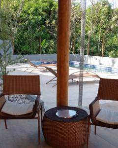 a patio with two chairs and a table at Casa em Village Jardim Itaitu in Caém