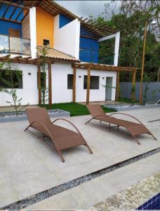 two brown chairs sitting on a patio in front of a house at Casa em Village Jardim Itaitu in Caém
