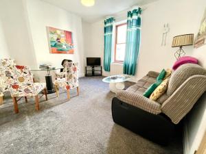 a living room with a couch and chairs and a table at 3 bedroomed house for up to 7 people, close to The Hoe, Barbican & City Centre in Plymouth