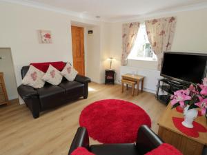 a living room with a couch and a flat screen tv at Bodegri Cottage in Llanfflewyn