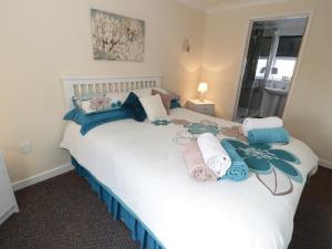 a bedroom with a large white bed with towels on it at Bodegri Cottage in Llanfflewyn