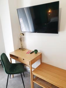 a desk with a green chair and a television on a wall at B&B Castelluccio in Villafranca Tirrena