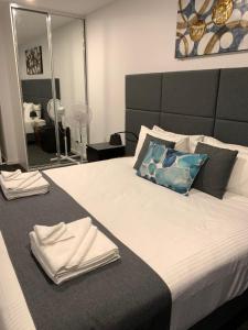 a bedroom with a large bed with towels on it at The Palms Apartments in Adelaide