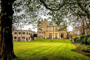 a large house on a grassy field with a tree at Burnley North Oaks Hotel and Leisure Club in Burnley