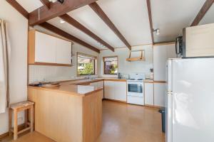 a kitchen with white cabinets and a refrigerator at Goodall Crib - Wanaka Holiday Home in Wanaka