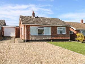 a brick house with a gravel driveway at Elliott's Retreat in Sheringham