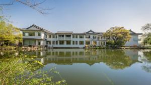 een groot huis met een meer ervoor bij West Lake State Guest House in Hangzhou