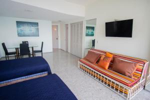 sala de estar con sofá y TV de pantalla plana en Suite frente al mar en el corazón de Acapulco en Acapulco
