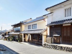 uma rua com um edifício com um banco em frente em Hostel & Tatami Bar Uchikobare -内子晴れ- em Uchiko