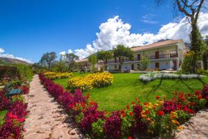 a garden of flowers in front of a building at Hotel Agustos Urubamba in Urubamba