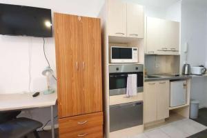 a small kitchen with white cabinets and a microwave at Compact City Studio In The Uni Disctrict in Auckland