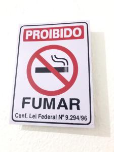 un panneau portant un panneau interdisant de fumer sur un mur dans l'établissement Aeroporto House 2, à Macapá