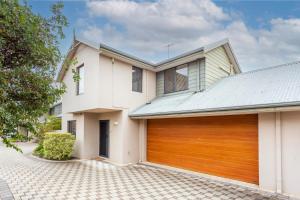 a white house with a wooden garage door at Coode Street Townhouse in Perth