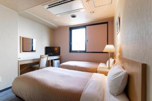 a hotel room with two beds and a desk at Kanazawa Central Hotel in Kanazawa