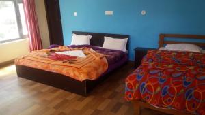 1 dormitorio con 2 camas y pared azul en Vamoose Maa Bhawani Munsiyari, en Munsyari