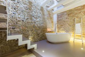 a bathroom with a white tub and a stone wall at Residenza Amblingh in Vasto