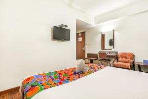 a hotel room with a bed and a tv at FabHotel Sri Krishna Suites Bellandur in Bangalore