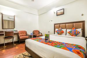 a bedroom with a bed and a desk and chairs at FabHotel Sri Krishna Suites Bellandur in Bangalore