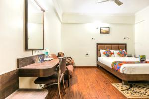 a hotel room with a bed and a desk and a bed at FabHotel Sri Krishna Suites Bellandur in Bangalore