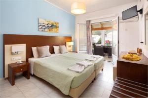 a bedroom with a large bed and a balcony at Dandidis Seaside Pension in Agios Gordios