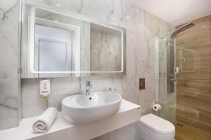 a white bathroom with a sink and a toilet at Dandidis Seaside Pension in Agios Gordios