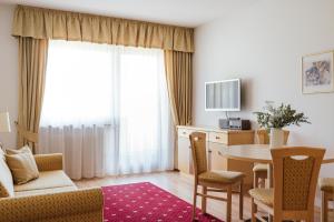 Hotel Bauhof في كاستلبيلو: غرفة معيشة مع طاولة وكراسي وتلفزيون
