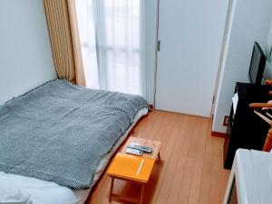 - une petite chambre avec un lit et une table dans l'établissement Luxes Hiroshima2F ラクセス ヒロシマ2F, à Hiroshima