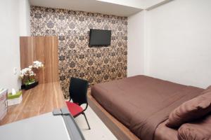 ein Schlafzimmer mit einem Bett und einem Fernseher an der Wand in der Unterkunft D'Paragon Seturan 3 in Yogyakarta