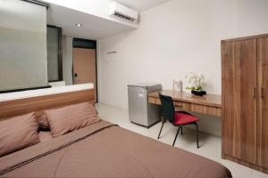 ein Schlafzimmer mit einem Bett, einem Schreibtisch und einem Stuhl in der Unterkunft D'Paragon Seturan 3 in Yogyakarta