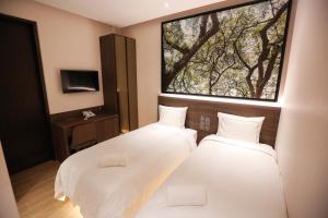 two beds in a room with a large window at L Hotel at Bugis Ville in Singapore