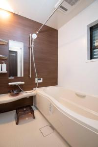 ein Badezimmer mit einer Badewanne, einem Waschbecken und einem Spiegel in der Unterkunft Tsumugian in Housai