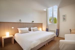 Un dormitorio con una gran cama blanca y una ventana en Hotel La Maison de la Prade en Messanges