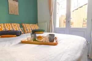 a tray with food and glasses on a bed at Le Chanzy-Terrasse privative in Saumur