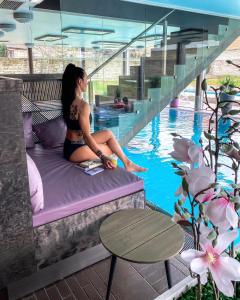 uma mulher sentada numa cama ao lado de uma piscina em Johan Design & SPA Hotel em Kuressaare