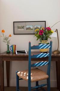 Sonoma Creek Inn في سونوما: كرسي ازرق جالس في مكتب فيه مزهرية ورد