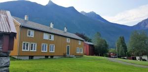 una casa su un campo con montagne sullo sfondo di Lensmansgarden Marteinsgarden a Innfjorden