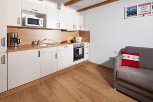eine kleine Küche mit weißen Schränken und einem Sofa in der Unterkunft Gästehaus Untersulzberglehen in Schönau am Königssee