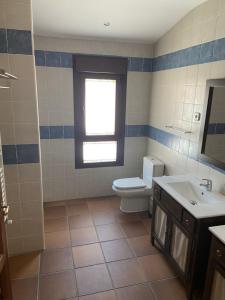 a bathroom with a toilet and a sink and a window at Casa Rural San Isidro in Valdepiélagos +31 photos