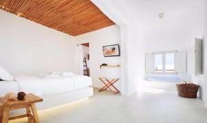 Cette chambre blanche comprend un lit et une table. dans l'établissement Rocabella Santorini Hotel & Spa, à Imerovigli