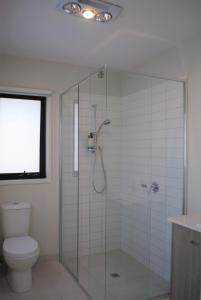 a bathroom with a glass shower with a toilet at BeachTownhouse779 in Rosebud