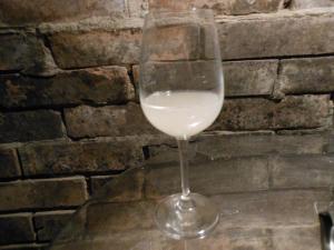 a glass of white wine sitting in front of a brick wall at Merum Pincészet és Vendégszoba in Tállya