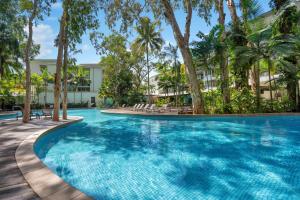 a swimming pool with palm trees and a building at Elysium The Drift in Palm Cove