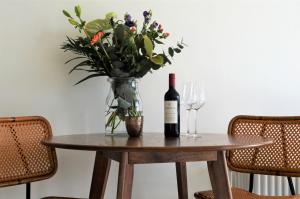 een tafel met een fles wijn en een vaas met bloemen bij The Sunset Apartments in Hollum