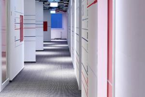 an empty corridor of an office building with white walls and carpet at Maverick Budapest Soho in Budapest