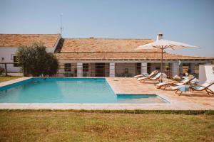 a pool with chairs and an umbrella next to a house at Casa Rural Sansaba in Seville