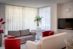 a living room with a couch and red chairs at Hotel Tre Rose in Caorle