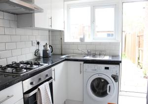 a kitchen with a washing machine and a sink at Private & Comfortable 2 Bedroom Home away from Home in Stanwell