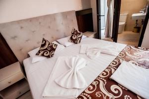 a bed with white sheets and black and white pillows at Jijo's Hotel in Mamaia