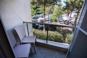 a balcony with two chairs and a view of a parking lot at Jijo's Hotel in Mamaia